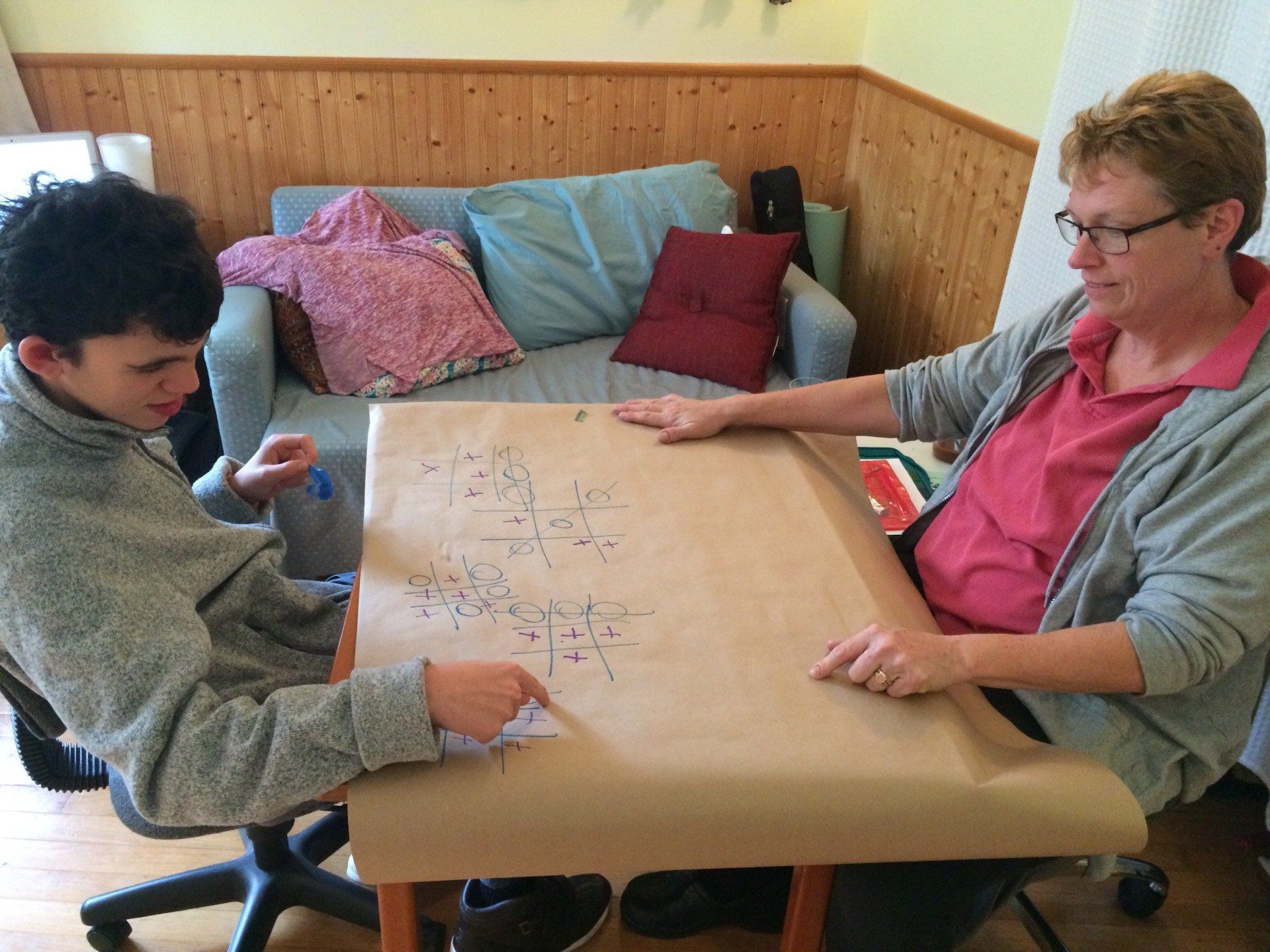 A woman and a boy are sitting at a table in front of a couch