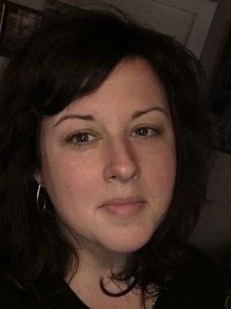 A close up of a woman 's face wearing a black shirt and earrings.