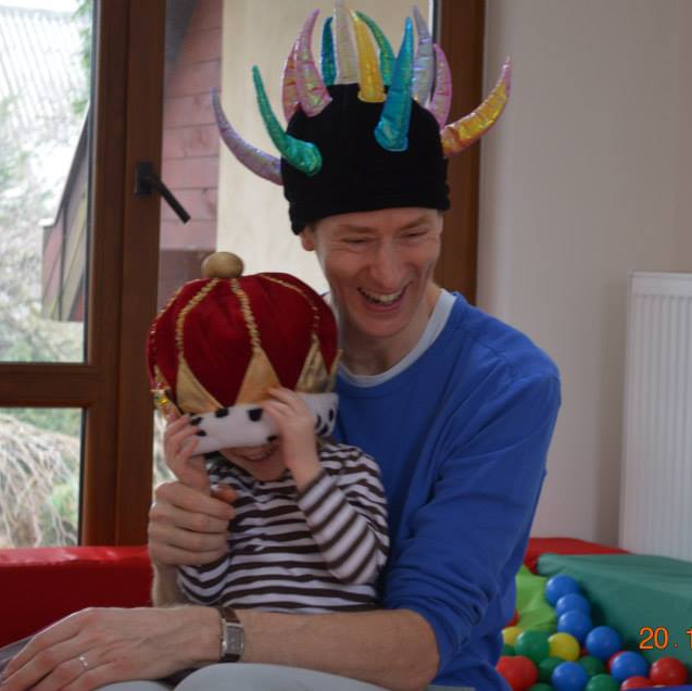 A man is holding a child wearing a viking hat