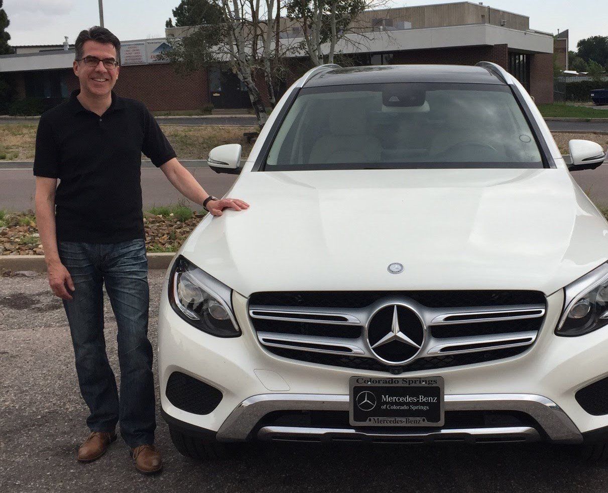 A man is standing in front of a white mercedes