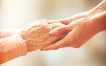Caretaker and senior holding hands