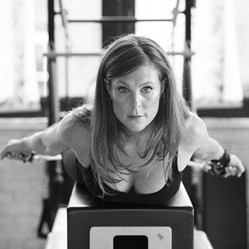 A woman is doing exercises on a pilates machine in a black and white photo.