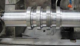 A metal cylinder with several attached rings on a grinding machine.