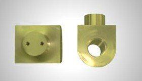 Two brass-colored metal components: one square with a circular protrusion and two holes, the other U-shaped with a circular hole.