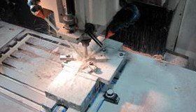 A CNC machine cutting metal, spraying sparks, and coolant.
