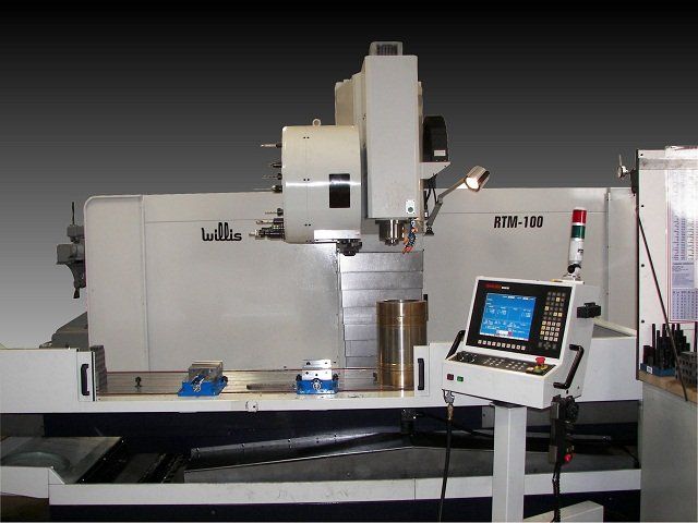 CNC milling machine with control panel and metal components on a workbench.
