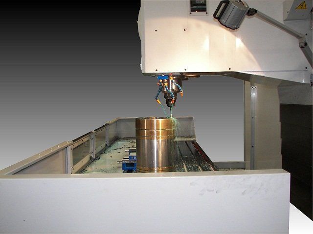 Machining equipment spraying liquid onto a cylindrical metal part.