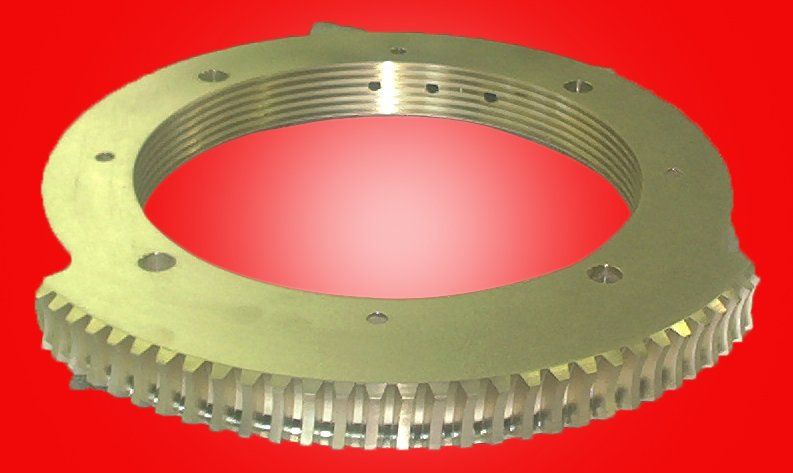 Gold-colored circular metal part with outer gear teeth, inner grooves, and mounting holes.