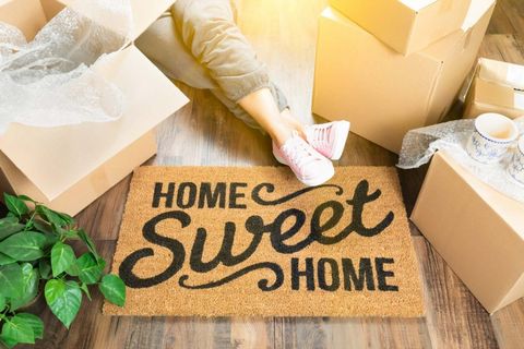 Woman sitting on floor of living room with Home Sweet Home door mat