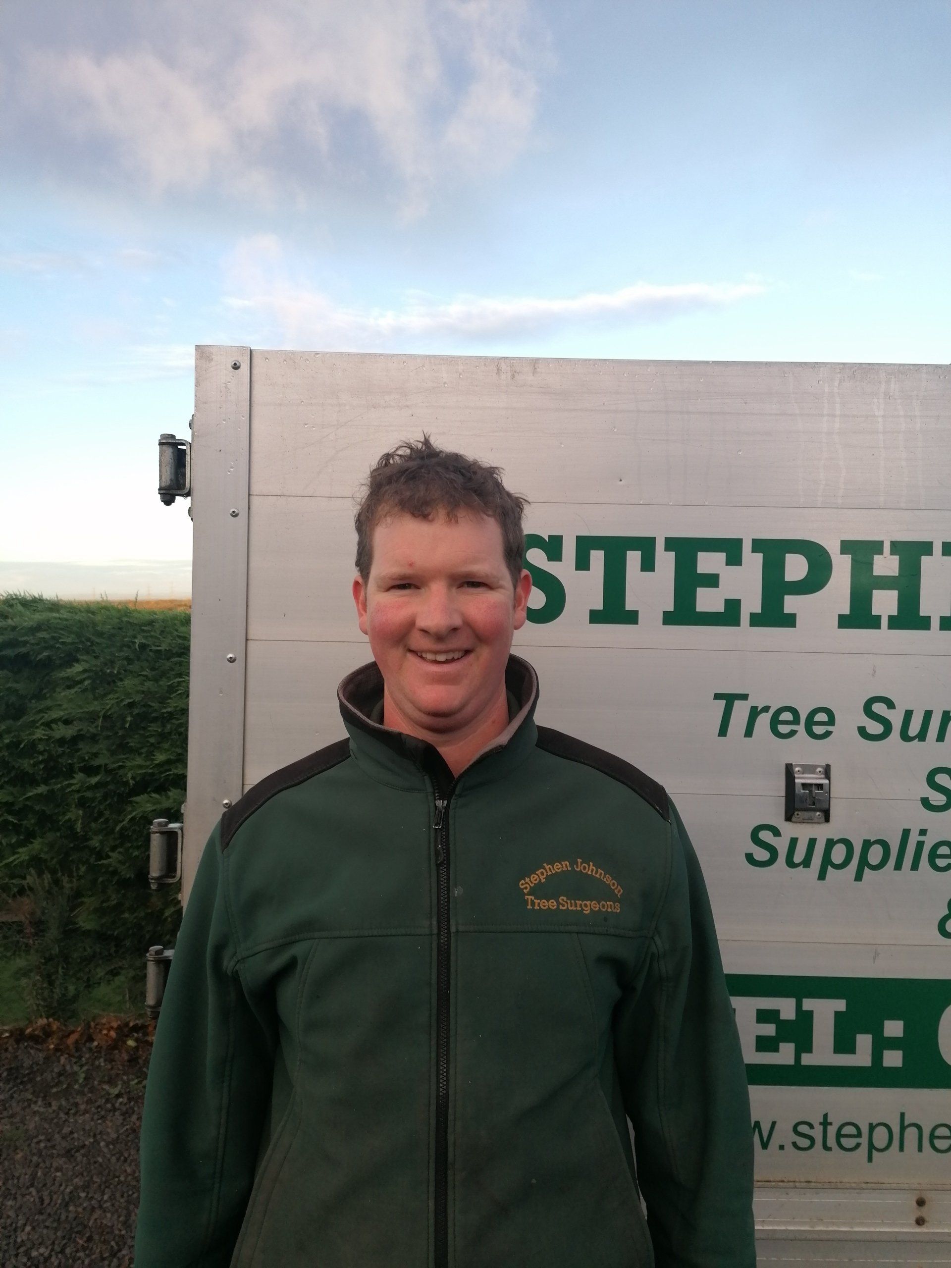 A man standing in front of a stephens tree supply truck