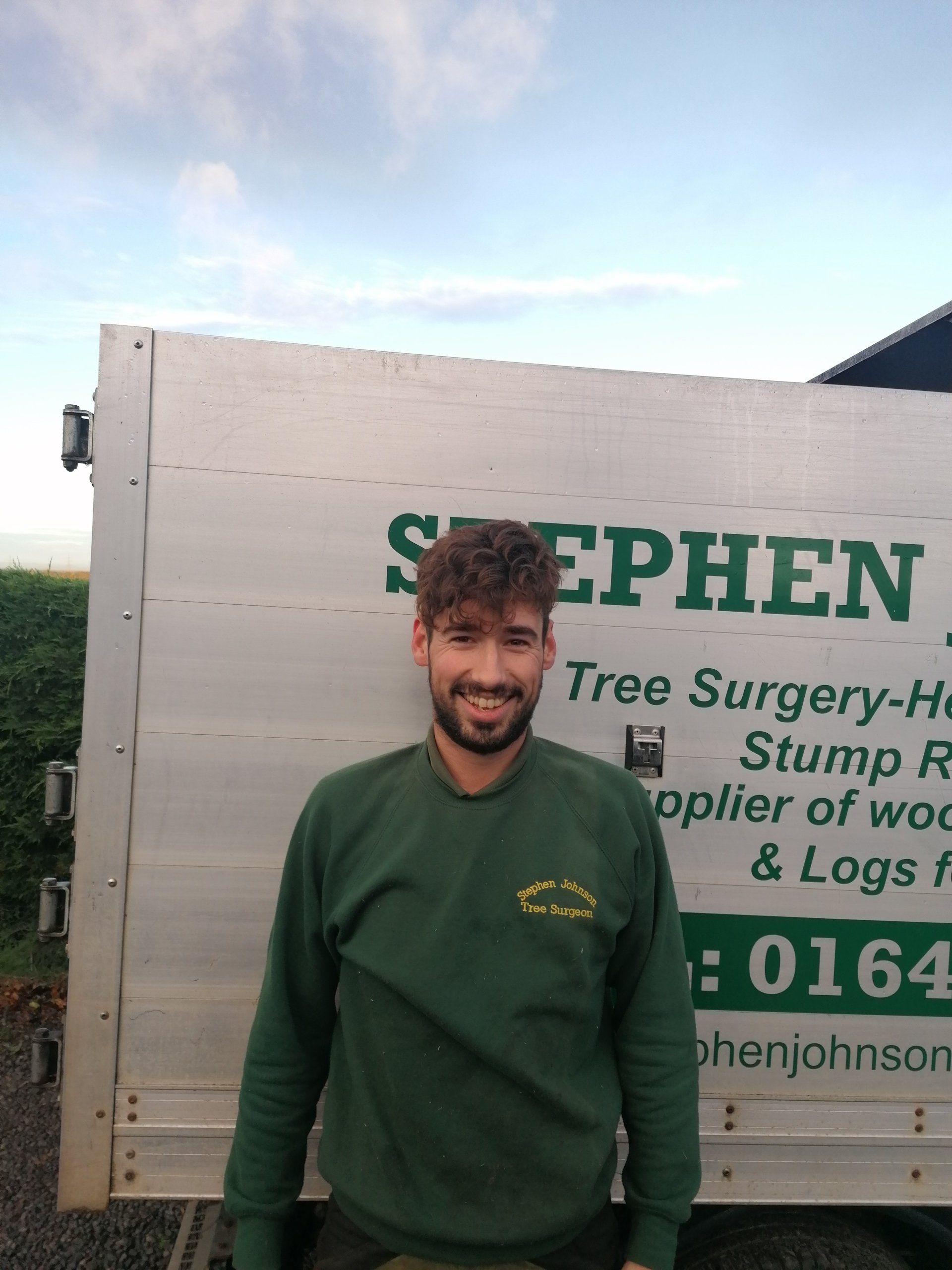 A man is standing in front of a stephen tree surgery truck.