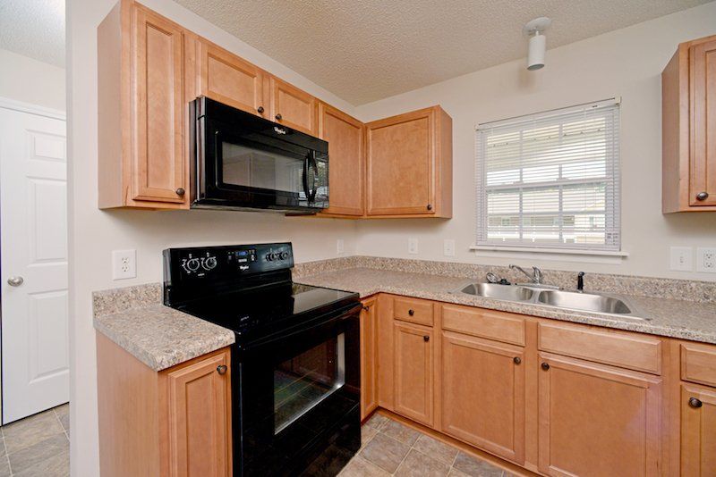 beacon kitchen with brown cabinets, window over sink, and black appliances 