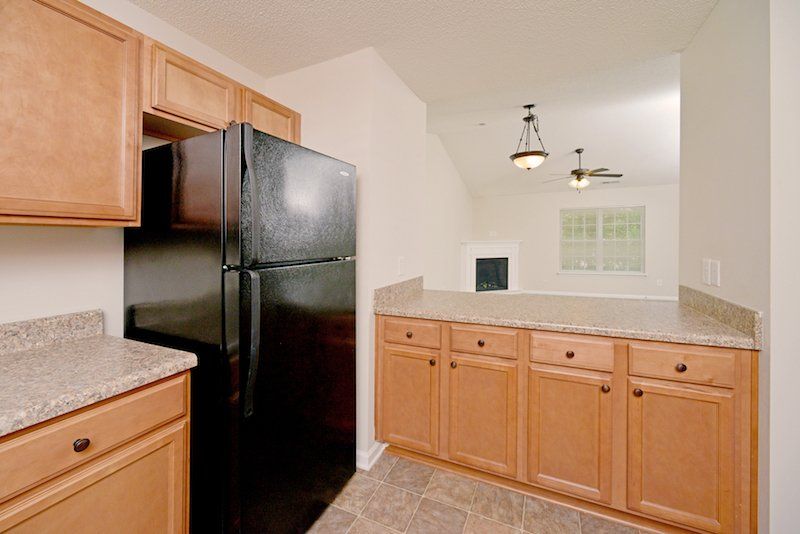 beacon kitchen with brown cabinets, window over sink, and black appliances - view of living room & dining room