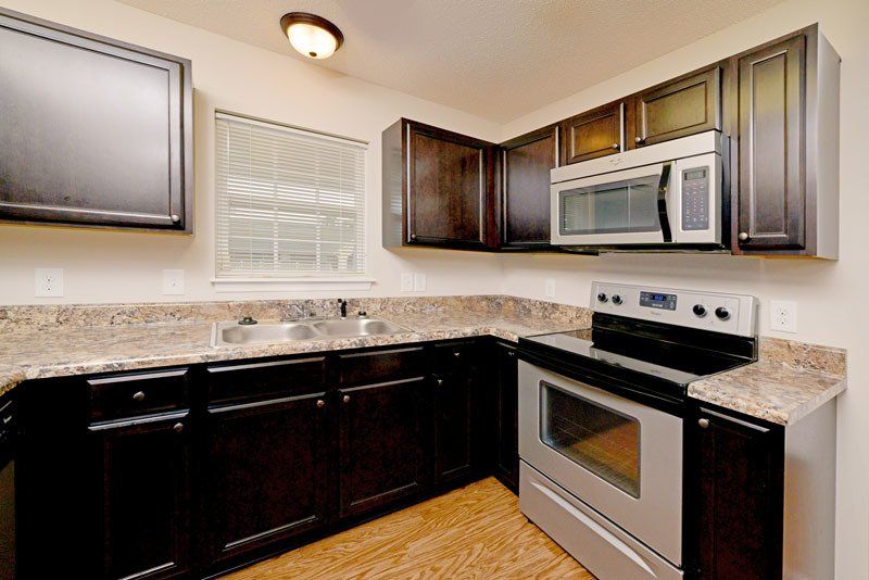 Beacon with dark brown cabinets, stainless steel appliances, and window above sink
