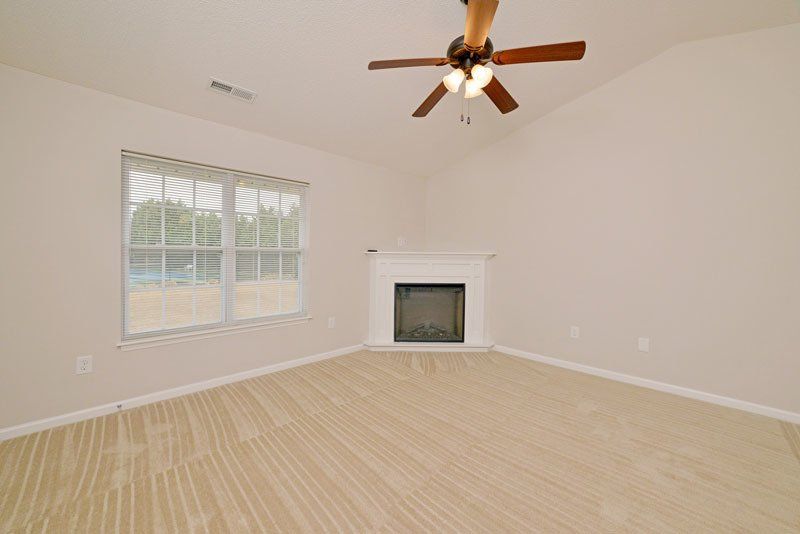 Beacon corner fireplace view with cathedral ceilings and ceiling fan. 