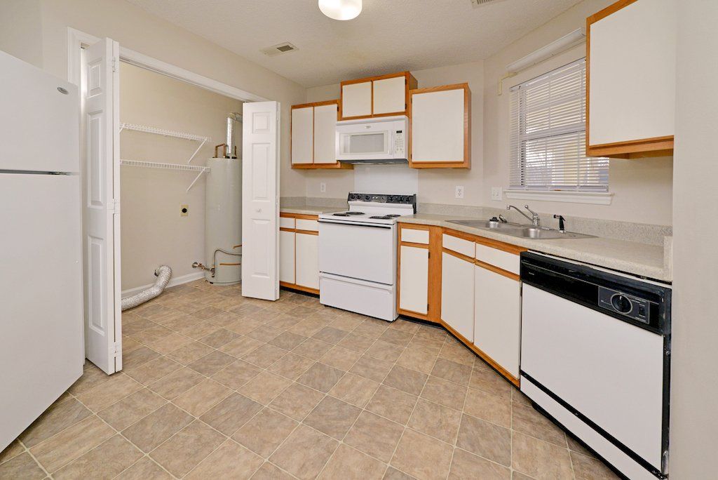 Pinnacle kitchen with 2-tones cabinets, white appliances, and closet door into the laundry room area