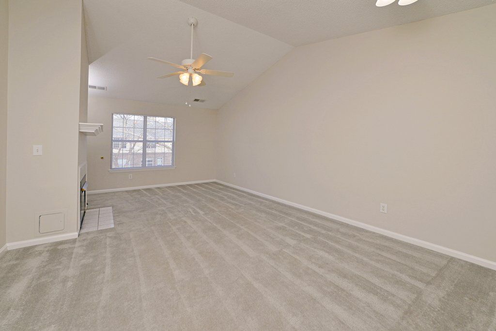 pinnacle view of living room: fireplace, cathedral ceilings, ceiling fan, window