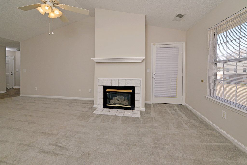 pinnacle view of living room: fireplace, cathedral ceilings, ceiling fan, window