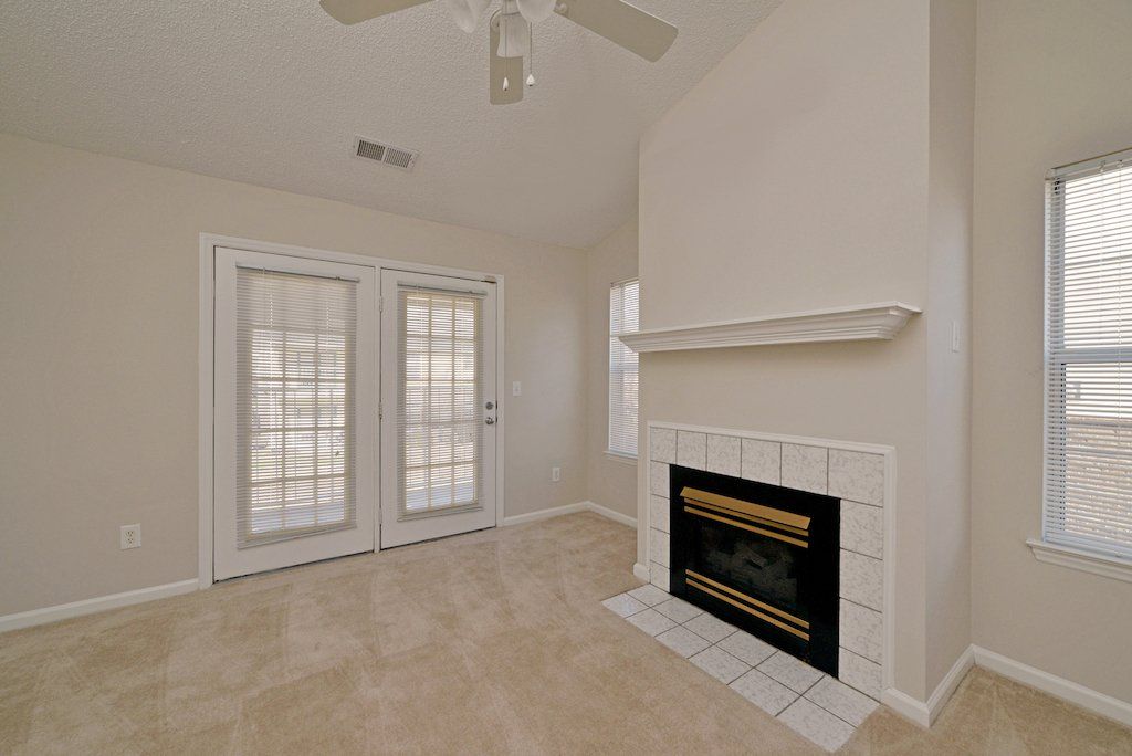Summit view of fireplace, carpeted flooring, windows, backdoors, and ceiling fan. 