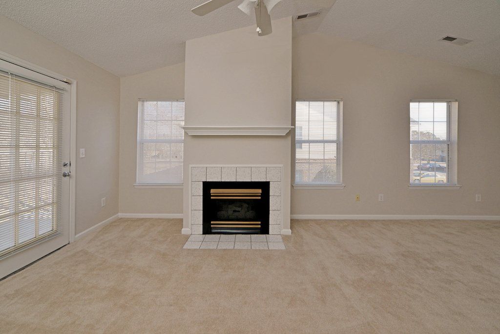 Summit view of fireplace, carpeted flooring, windows, backdoors, and ceiling fan. 