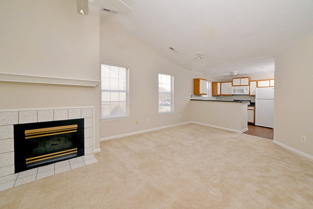 Summit view of fireplace, carpeted flooring, windows, backdoors, kitchen, and ceiling fan. 