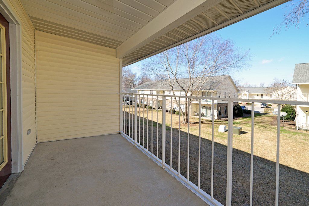 Summit upstairs patio facing other apartment buildings with green area in between with trees