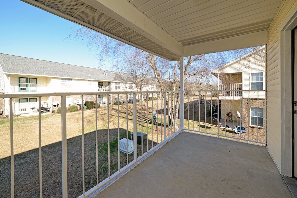 Summit upstairs patio facing other apartment buildings with green area in between with trees