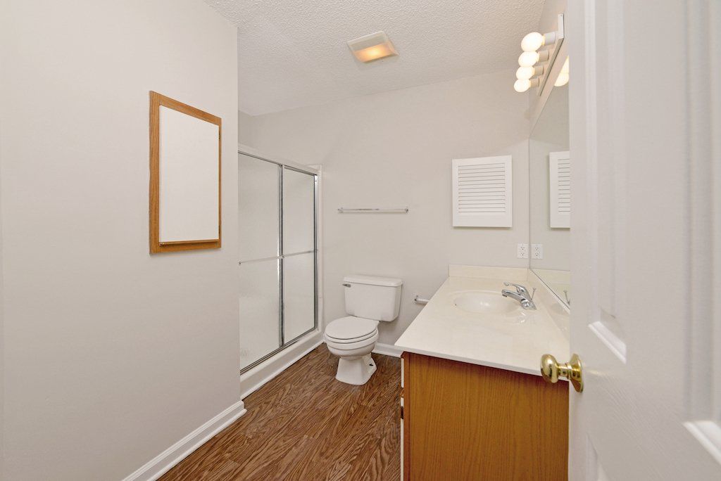 Summit guest bathroom shower, toilet, sink, with small space in wall for storage. 2-toned cabinets.