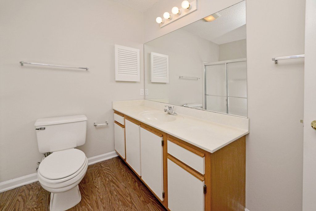 Summit guest bathroom view from corner shower, toilet, sink, with small space in wall for storage. 2-toned cabinets.