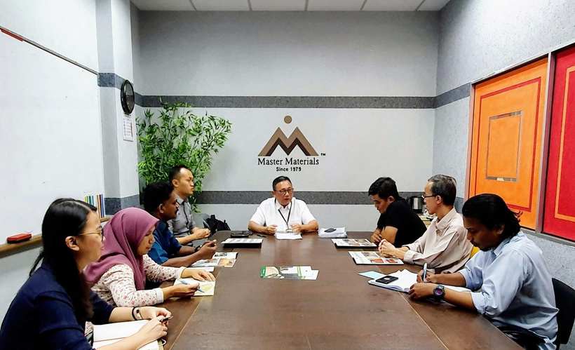 People seated around a conference table in an office, engaged in a meeting.