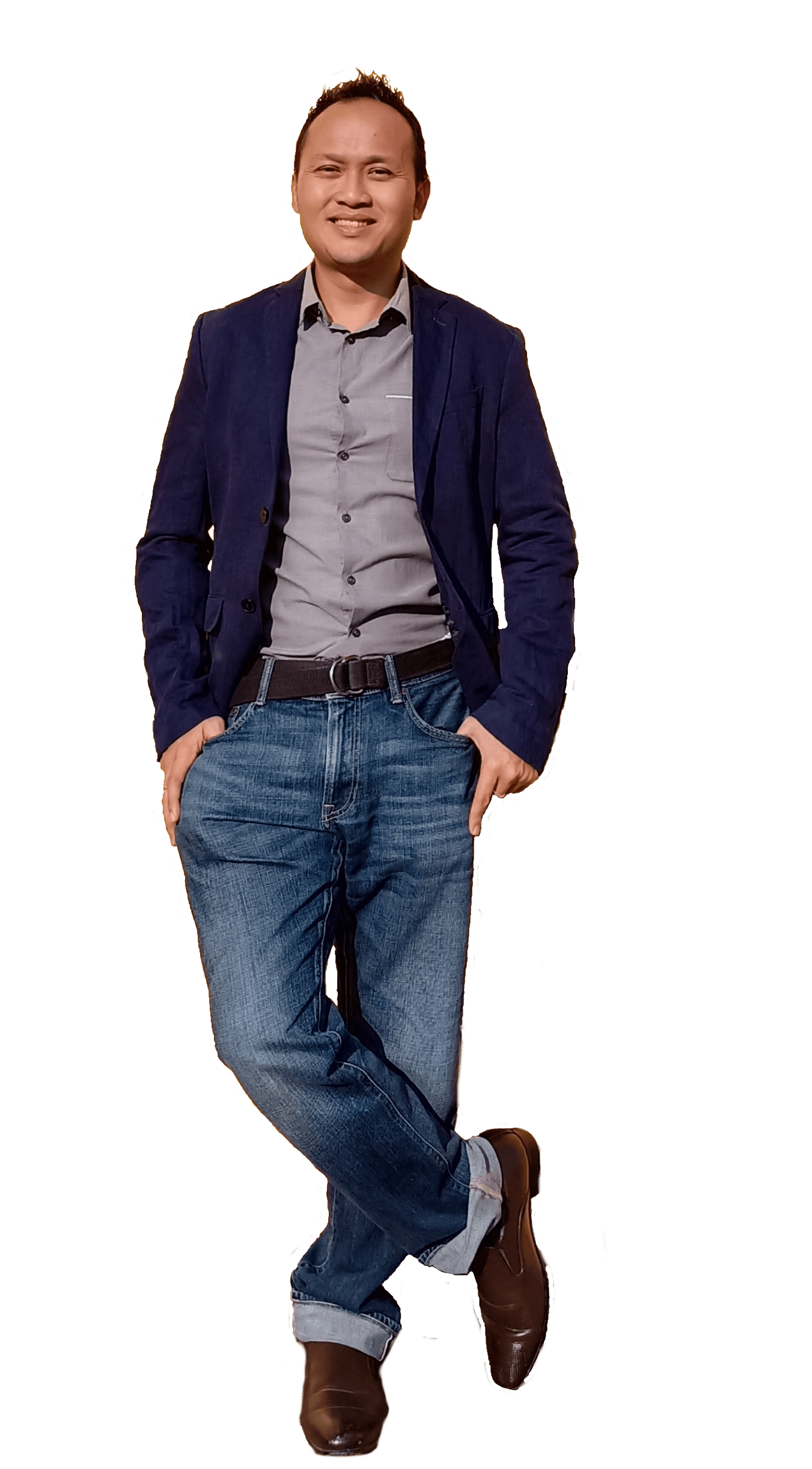 Man in blazer, gray shirt, and jeans, smiling, standing with crossed legs, hands in pockets.