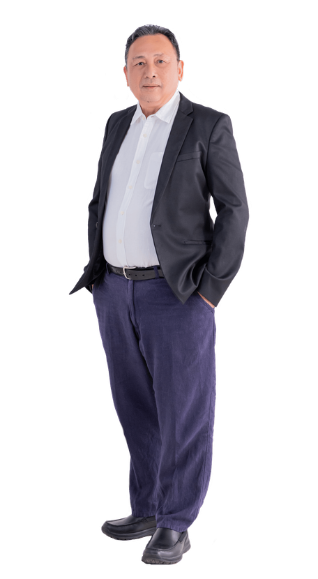 Man in a suit jacket, white shirt, and blue pants, hands in pockets, posing against a white background.