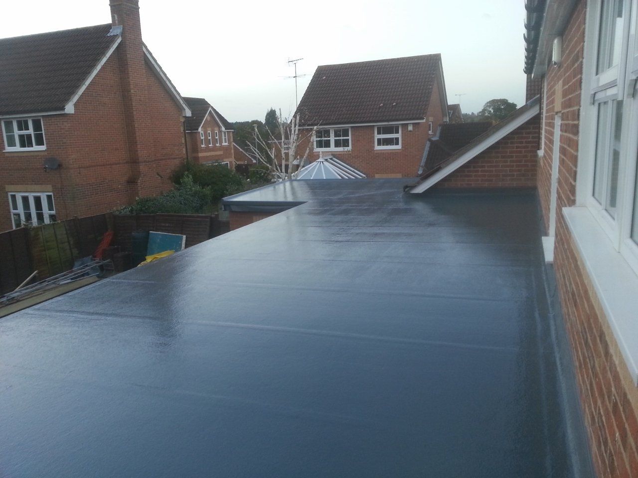 A black roof with a brick building in the background.
