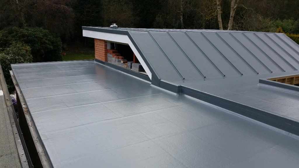 A close up of a roof with a gray roof and trees in the background.