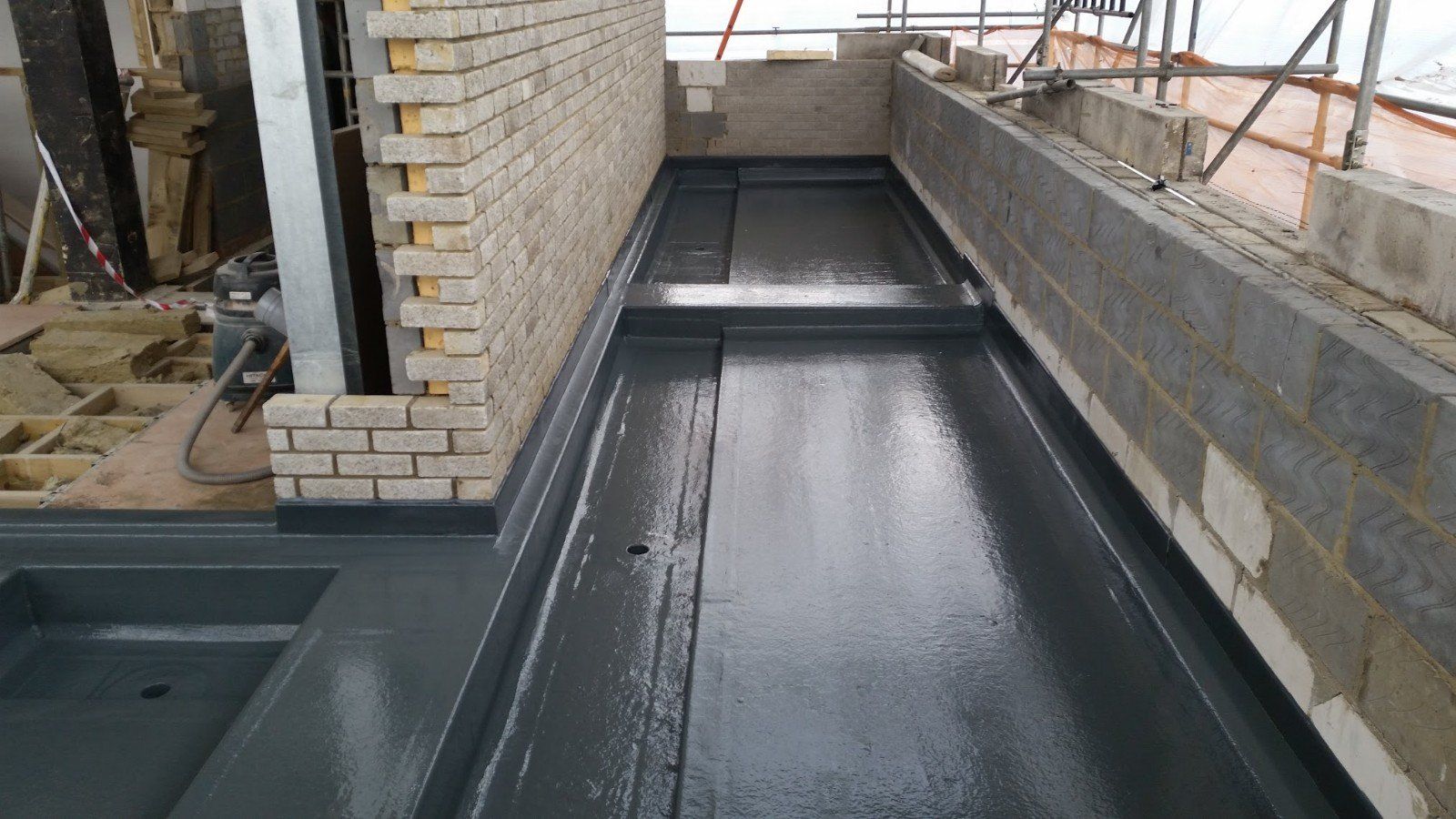 A building under construction with a brick wall and a concrete floor.