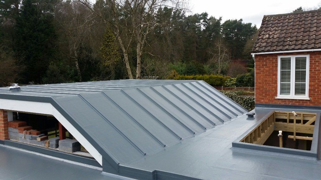 A roof of a house with a window and trees in the background.
