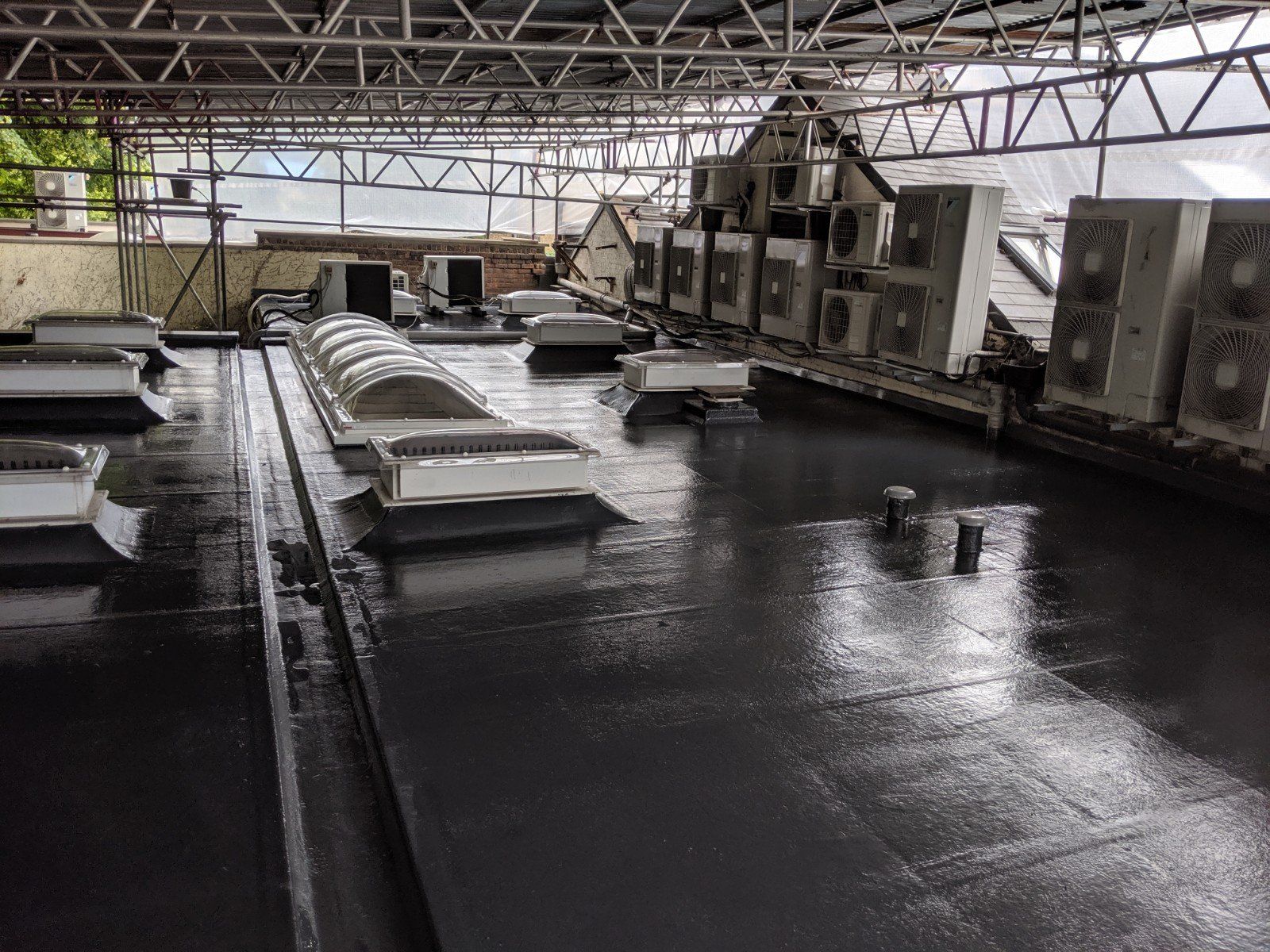 There are a lot of air conditioners on the roof of a building.