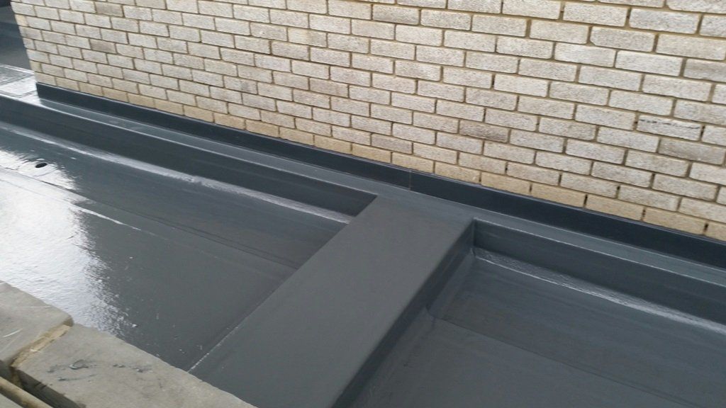 A brick wall with a drain on the side of it.