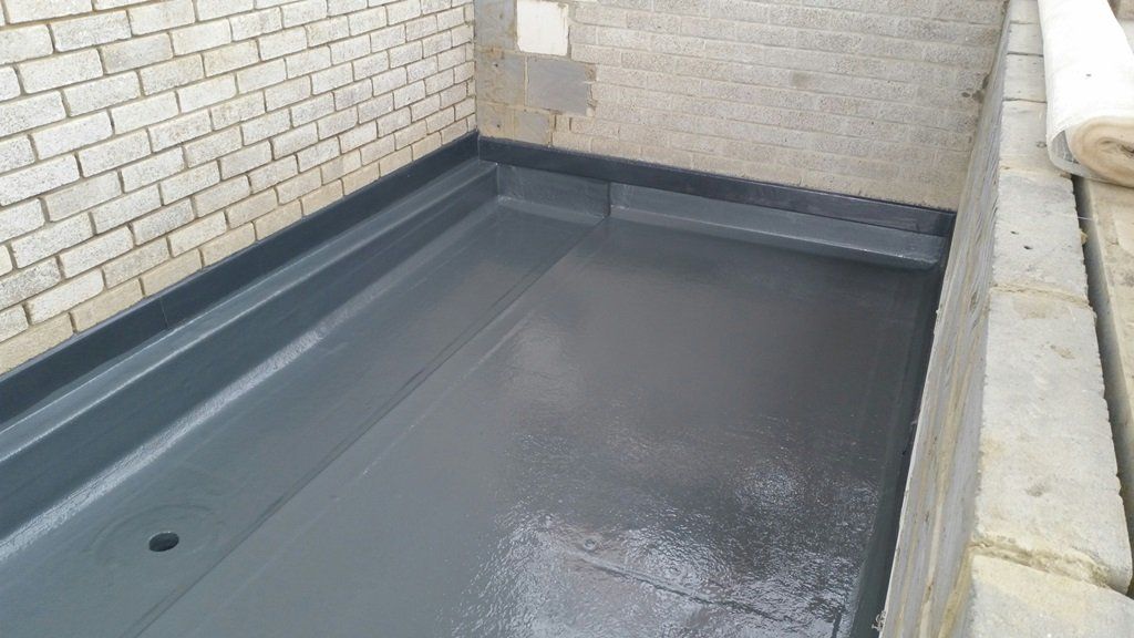 A brick wall with a concrete floor in front of it.