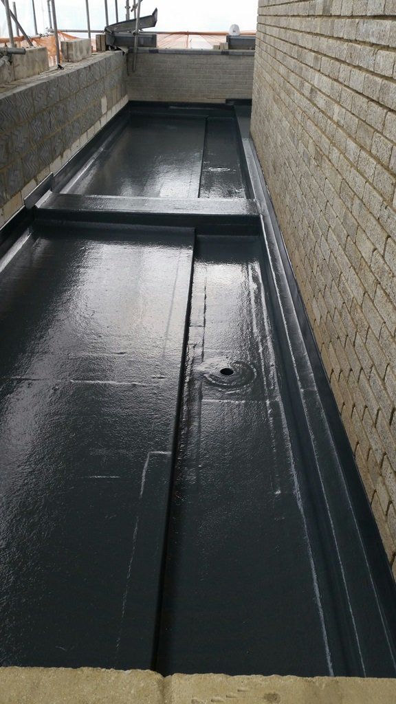 A black roof with a drain on the side of a building.