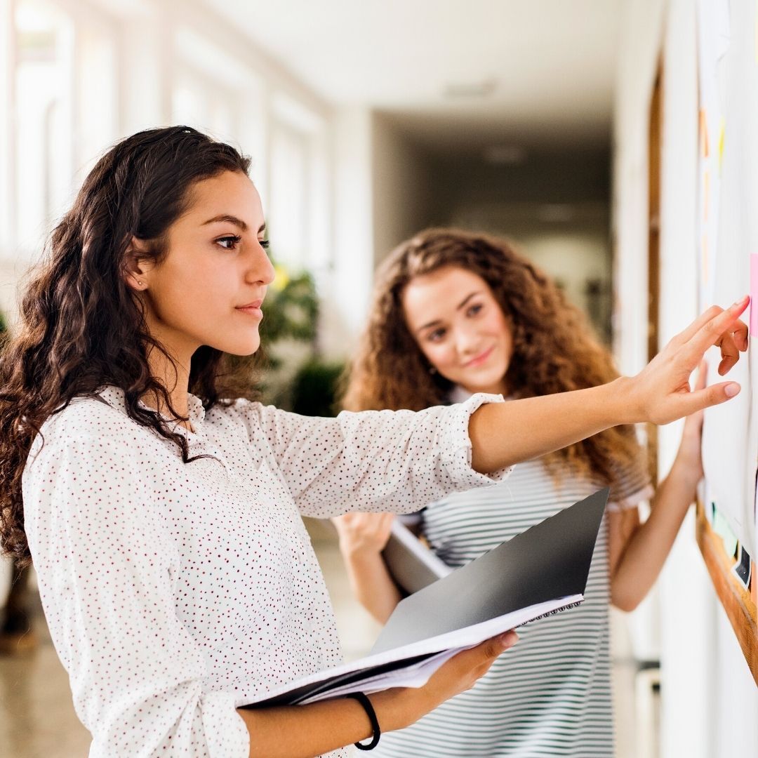 meninas olhando informação em quadro de avisos