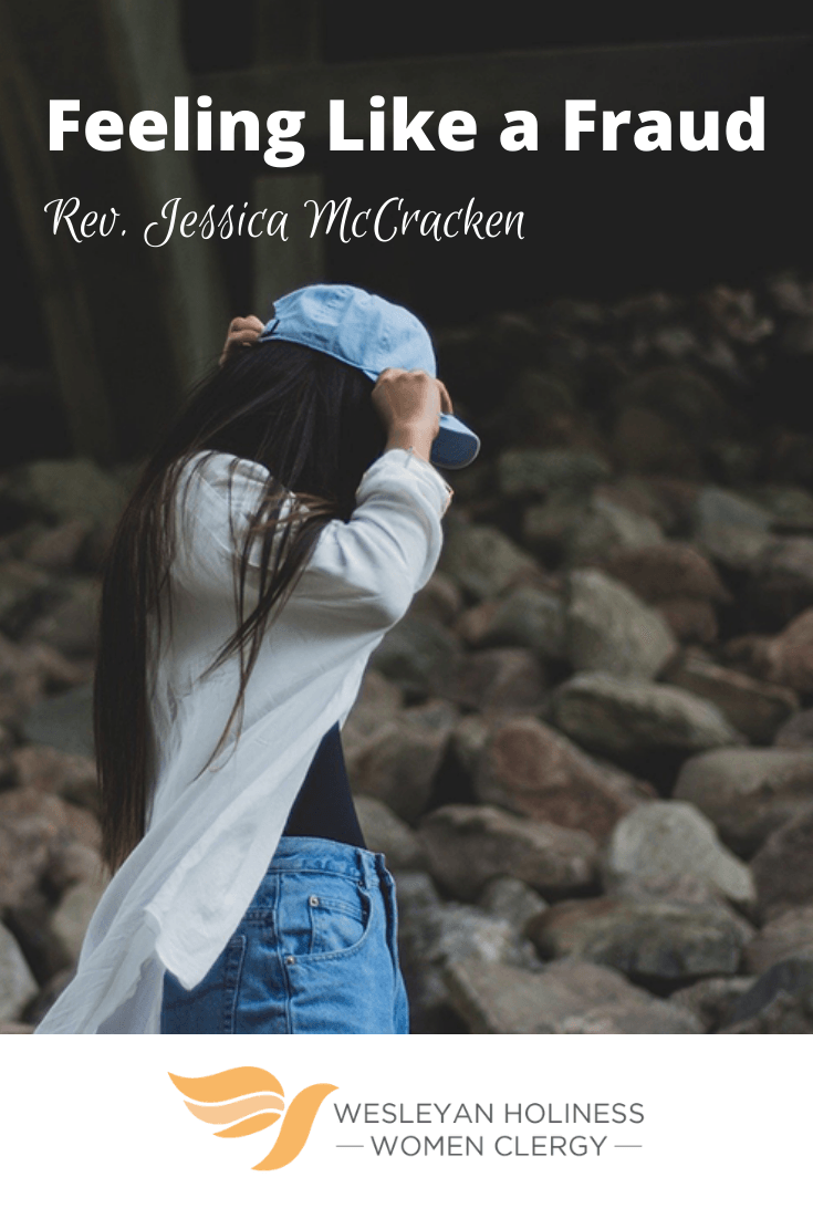 Girl walking with face covered, adjusting her hat.
