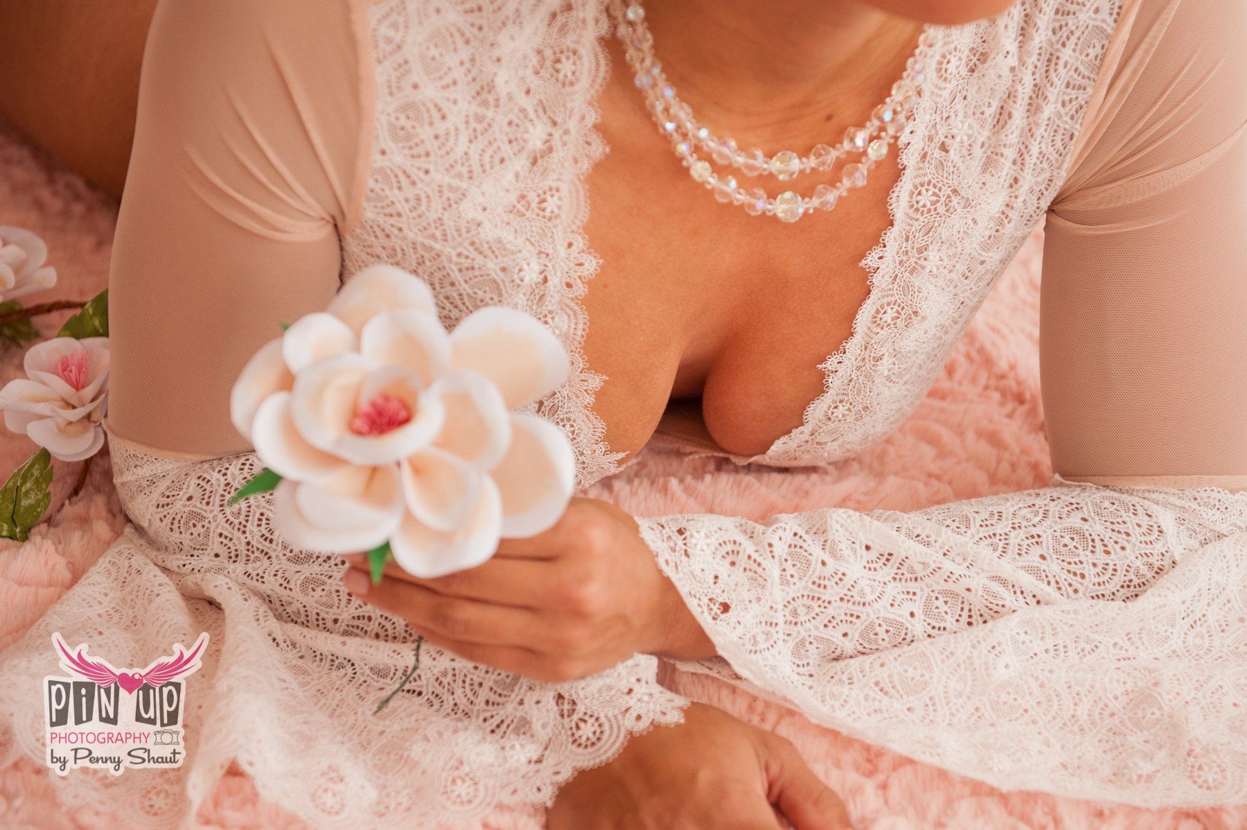 a woman is laying on a bed holding a white flower .