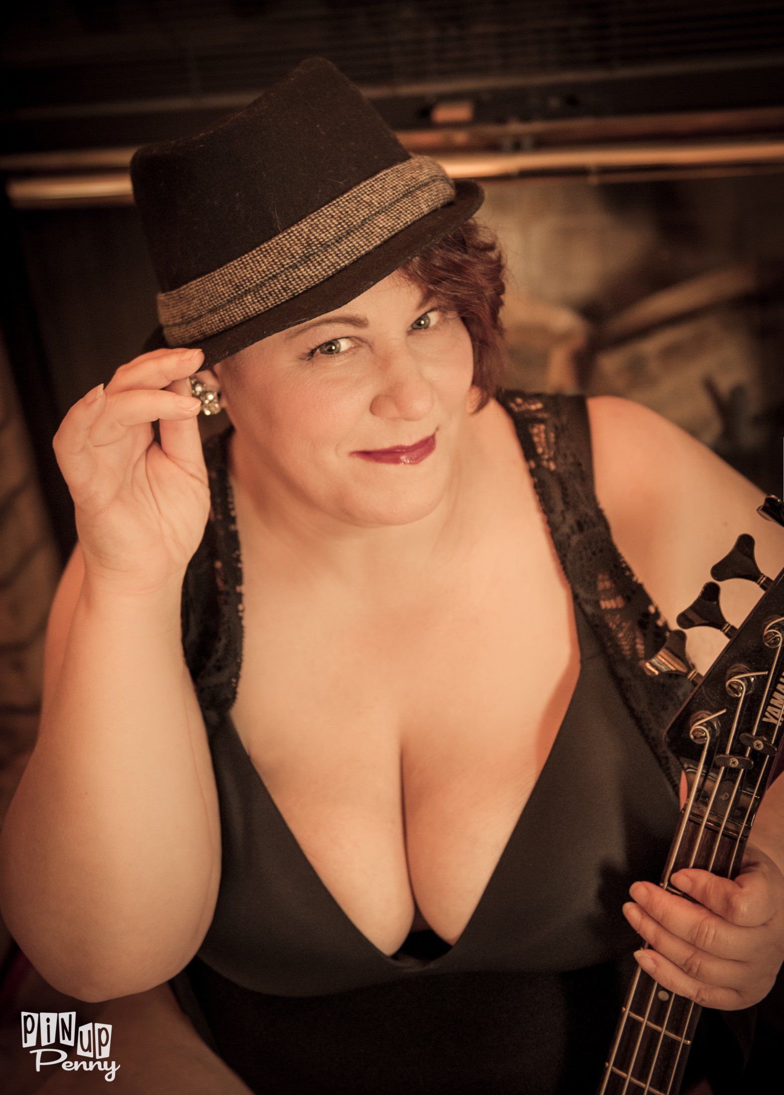 a woman in a hat is holding a bass guitar