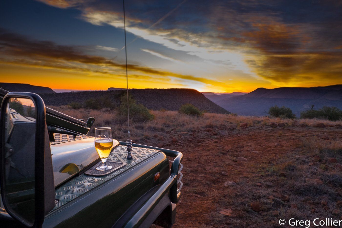 Sun setting with a glass of wine on the front of a tour car