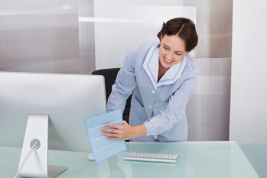 Portrait Of Happy Female Janitor Cleaning Desk At Office