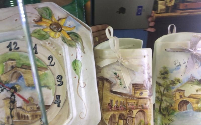 Orologio e due candele decorati con paesaggi italiani dipinti.