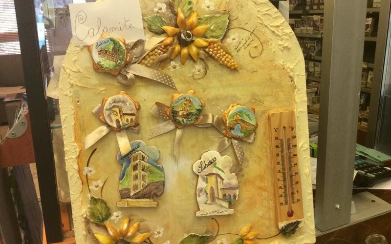 Appendino da parete con medaglioni colorati in ceramica raffiguranti scene di città e termometro.