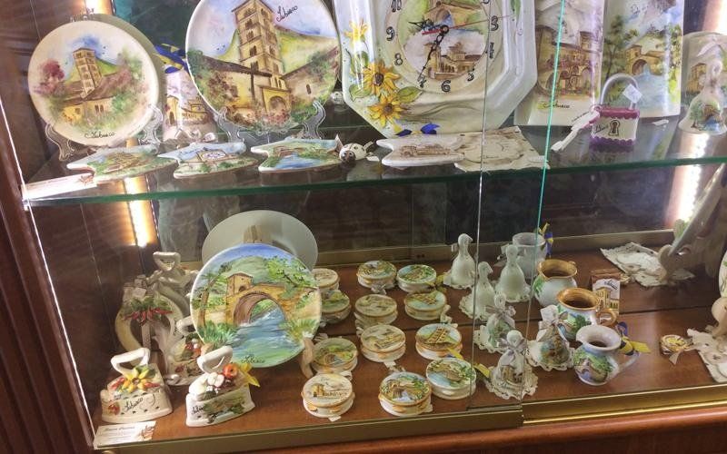 Vetrina piena di piatti decorativi, scatole portaoggetti e statuette.