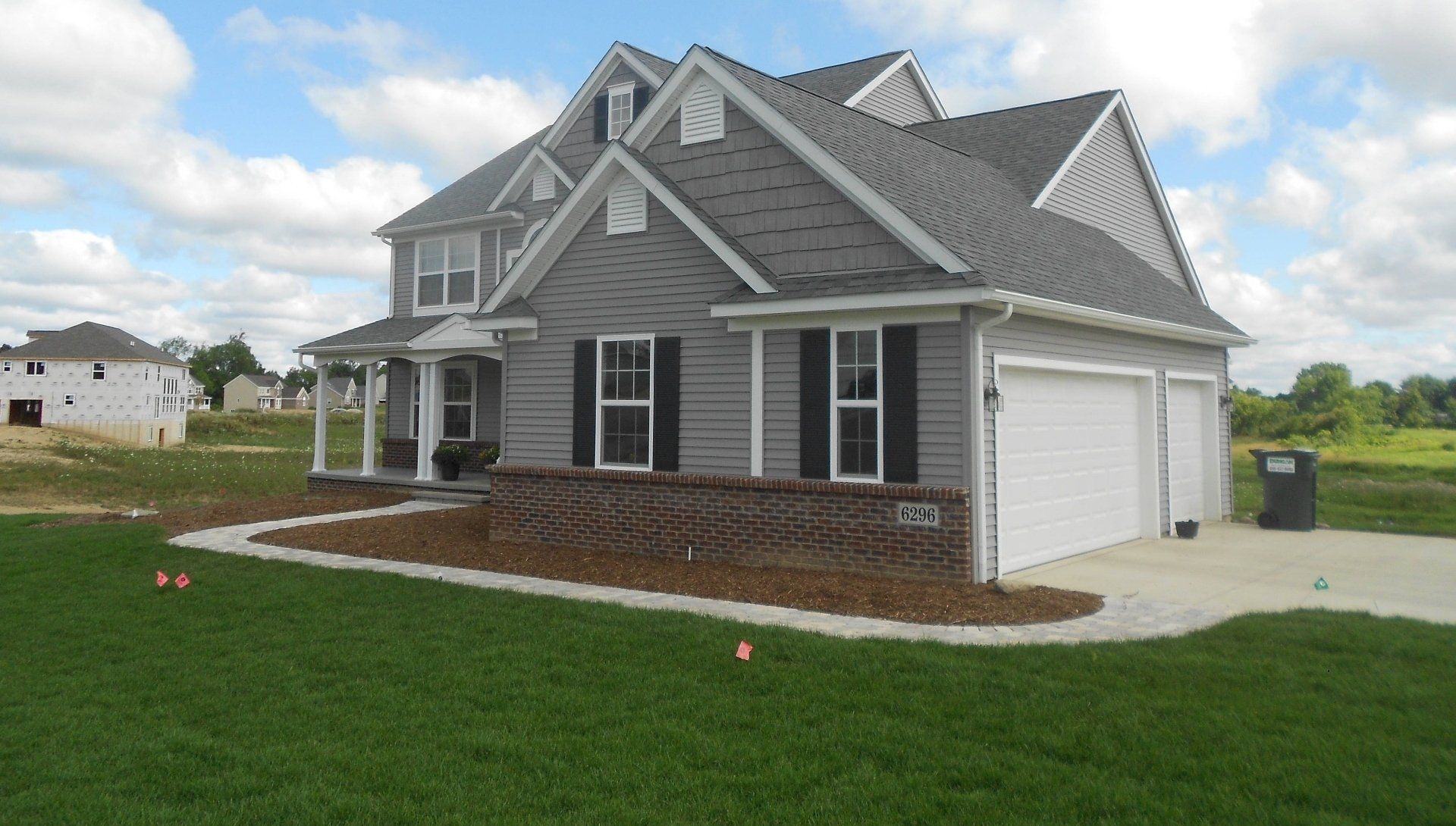 Gray suburban house with white trim, gabled roof, and two-car garage on a green lawn